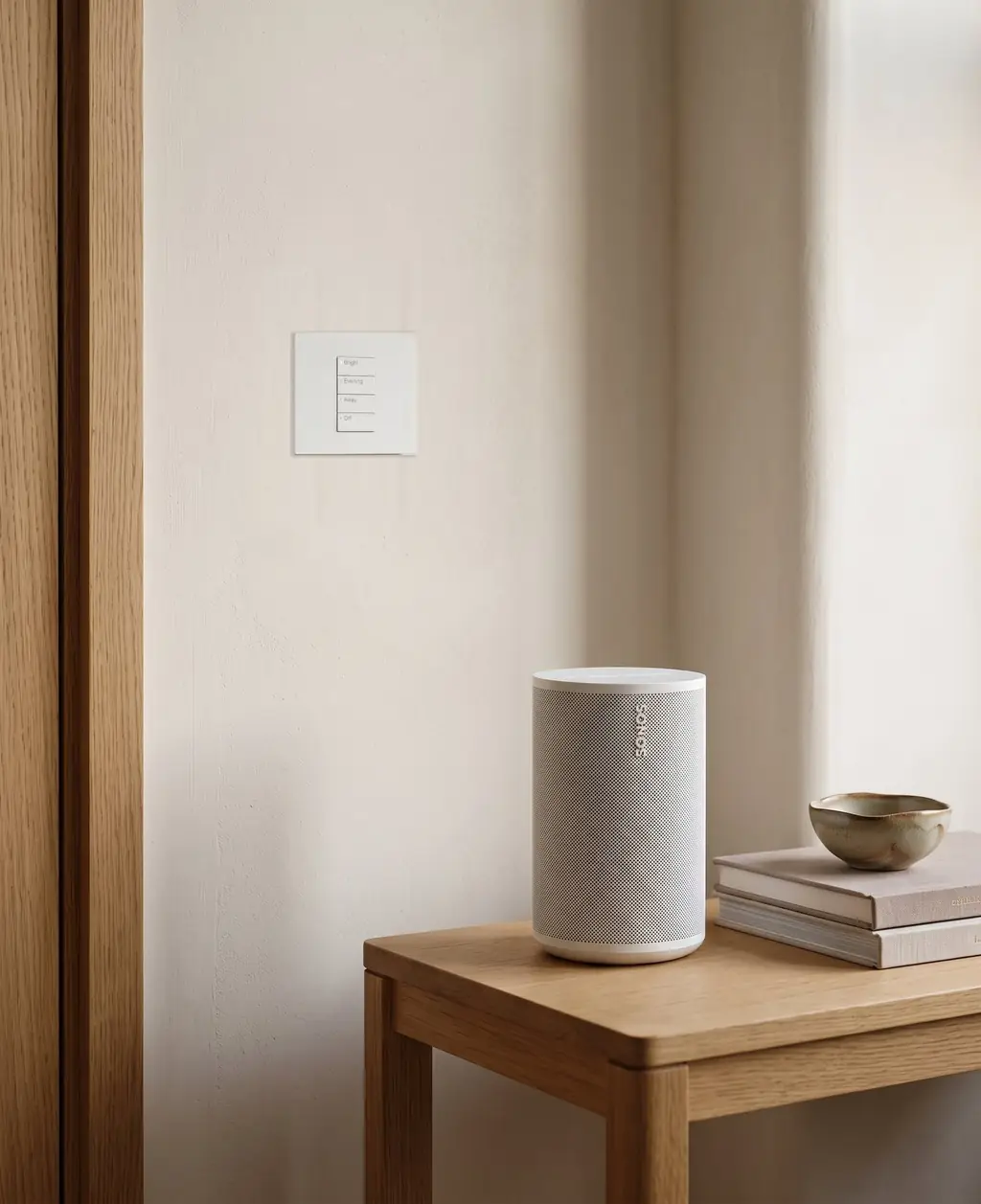 A white keypad on a wall above a speaker on a side table